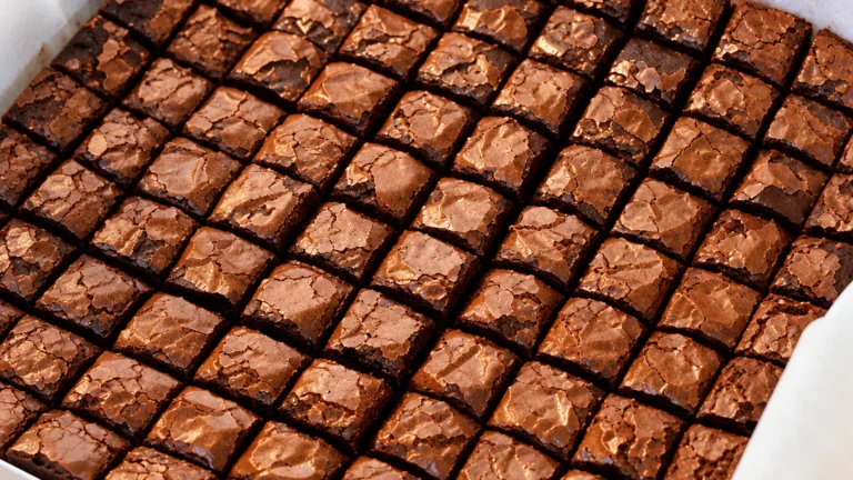 Brownie bites: dezenas de cubinhos de brownie com casquinha brilhante dentro de uma caixa forrada com papel manteiga